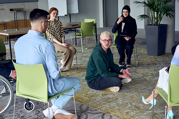 Image showing A man sitting at the center of a circle, passionately sharing his business ideas with his colleagues, fostering an atmosphere of collaboration and innovation in a dynamic and engaging workplace.