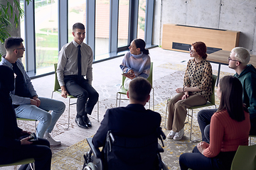 Image showing In a modern office, a diverse group of business individuals is seen gathered in a circle, engaged in lively discussions and sharing ideas about various business concepts.