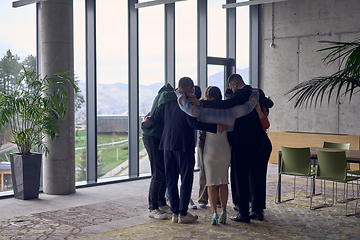 Image showing A diverse group of business professionals stand in each other's arms, and their smiles reflect the successful outcome of a joint effort and a shared vision of growth and prosperity.