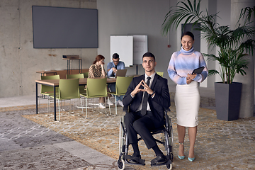 Image showing A businessman in a wheelchair and his female colleague together in a modern office, representing the power of teamwork, inclusion and support, fostering a dynamic and inclusive work environment.