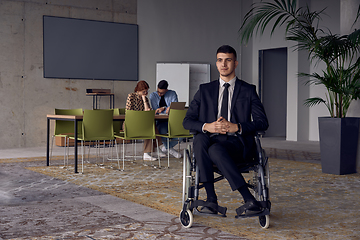 Image showing Businessman in a wheelchair commands attention, symbolizing resilience and success amidst a dynamic modern office environment.