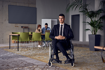 Image showing Businessman in a wheelchair commands attention, symbolizing resilience and success amidst a dynamic modern office environment.