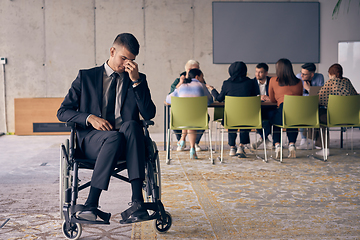 Image showing A melancholic businessman in a wheelchair sitting with a sad expression, gazing through the window of a modern office, conveying a sense of solitude