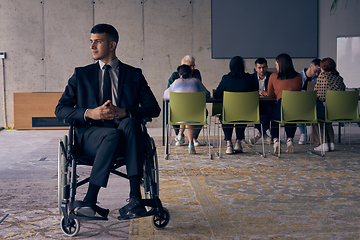 Image showing Businessman in a wheelchair commands attention, symbolizing resilience and success amidst a dynamic modern office environment.