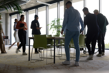 Image showing A diverse group of business professionals gathers around a table for meetings, engaging in discussions, collaboration, and strategic planning in a modern office