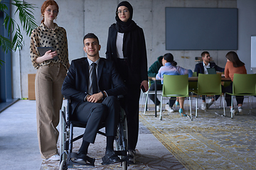 Image showing A businessman with disability in a wheelchair is surrounded by supportive colleagues in a modern office, showcasing the strength of teamwork, inclusivity, and empowerment in the face of challenges.