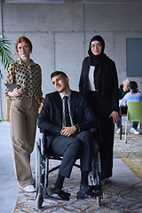 Image showing A businessman with disability in a wheelchair is surrounded by supportive colleagues in a modern office, showcasing the strength of teamwork, inclusivity, and empowerment in the face of challenges.