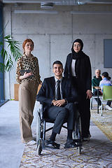 Image showing A businessman with disability in a wheelchair is surrounded by supportive colleagues in a modern office, showcasing the strength of teamwork, inclusivity, and empowerment in the face of challenges.