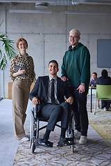 Image showing A businessman with disability in a wheelchair is surrounded by supportive colleagues in a modern office, showcasing the strength of teamwork, inclusivity, and empowerment in the face of challenges.