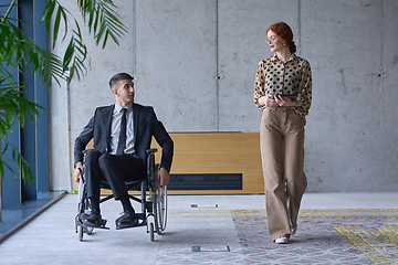 Image showing A businessman in a wheelchair and his female colleague together in a modern office, representing the power of teamwork, inclusion and support, fostering a dynamic and inclusive work environment.