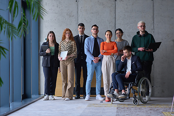 Image showing Diverse group of business people, including a businessman in a wheelchair in a modern office