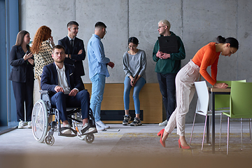 Image showing Diverse group of business people, including a businessman in a wheelchair in a modern office