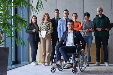 Image showing Diverse group of business people, including a businessman in a wheelchair in a modern office