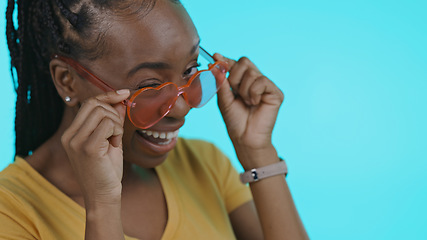 Image showing Face, funny and black woman with glasses, smile and heart on a blue studio background. Portrait, African person and happy model with funky eyewear, trendy and silly with fashion, mockup or happiness