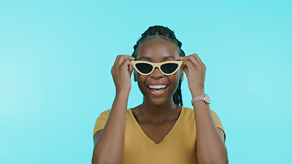 Image showing Face, happiness and black woman with glasses, silly or cheerful girl on a blue studio background. Portrait, African person or model with funky eyewear, trendy or goofy with casual outfit or happiness