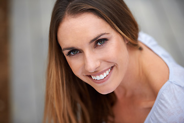 Image showing Smiling is the prettiest accesory you can wear. Portait of a young woman sitting outdoors.