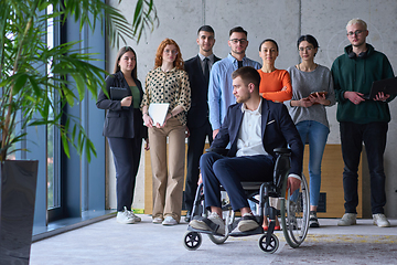 Image showing Diverse group of business people, including a businessman in a wheelchair in a modern office