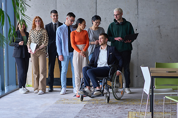 Image showing Diverse group of business people, including a businessman in a wheelchair in a modern office