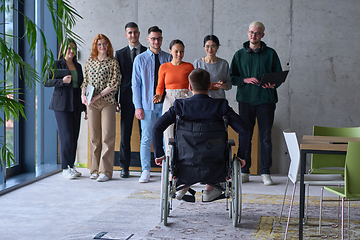 Image showing A group of diverse entrepreneurs gather in a modern office to discuss business ideas and strategies, while a colleague in a wheelchair joins them.