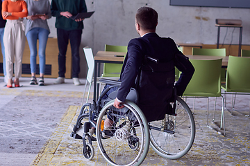Image showing A group of diverse entrepreneurs gather in a modern office to discuss business ideas and strategies, while a colleague in a wheelchair joins them.