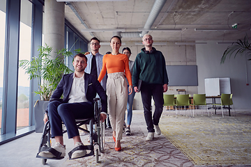 Image showing A diverse group of businessmen, including a businessman in wheelchair, confidently stride together through a modern, spacious office, epitomizing collaboration, inclusivity, and strength in unity