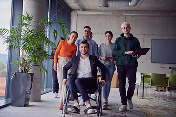 Image showing A diverse group of businessmen, including a businessman in wheelchair, confidently stride together through a modern, spacious office, epitomizing collaboration, inclusivity, and strength in unity