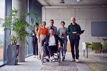 Image showing A diverse group of businessmen, including a businessman in wheelchair, confidently stride together through a modern, spacious office, epitomizing collaboration, inclusivity, and strength in unity