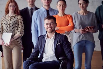 Image showing Diverse group of business people, including a businessman in a wheelchair in a modern office