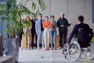 Image showing A group of diverse entrepreneurs gather in a modern office to discuss business ideas and strategies, while a colleague in a wheelchair joins them.