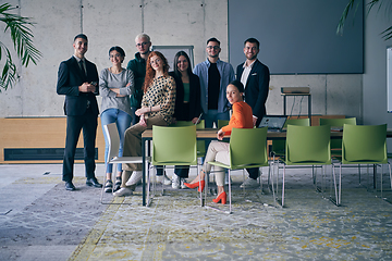 Image showing A diverse group of successful businesspeople gather and pose for a photo, showcasing teamwork and professional empowerment in a modern office setting.