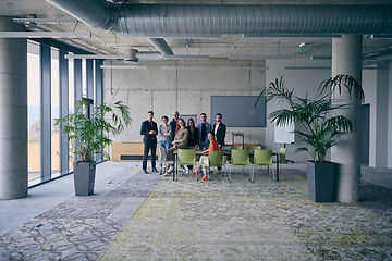 Image showing A diverse group of successful businesspeople gather and pose for a photo, showcasing teamwork and professional empowerment in a modern office setting.