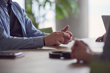 Image showing Closeup photo, the hands of businessmen sitting at a business meeting can be seen as they discuss various business ideas and engage in productive collaboration.