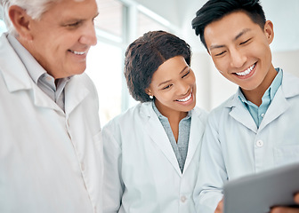 Image showing Using technology throughout their experiments. a group of scientists working together on a digital tablet in a lab.