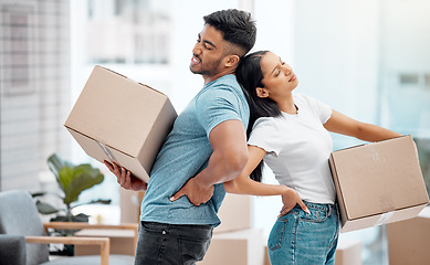 Image showing These boxes are so heavy. a young couple standing and suffering from backache while carrying boxes in their new home.