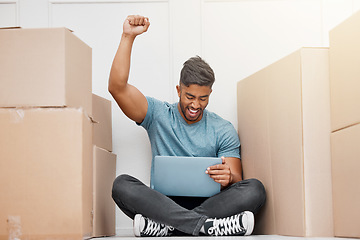 Image showing I got the apartment. Full length shot of a young man sitting in his new home and celebrating a success while using his laptop.
