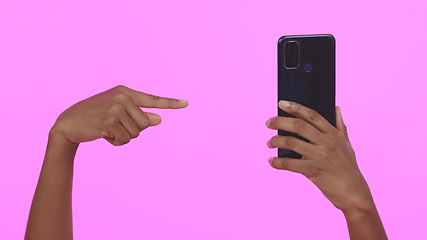 Image showing Studio, hand holding phone and pointing for contact, connectivity or mobile networking. Social media, website and person with smartphone technology for communication, app or choice on pink background