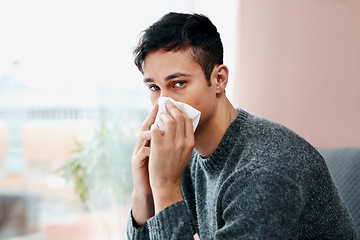 Image showing When flu season starts up so does my allergies. a young man blowing his nose while recovering from an illness in bed at home.
