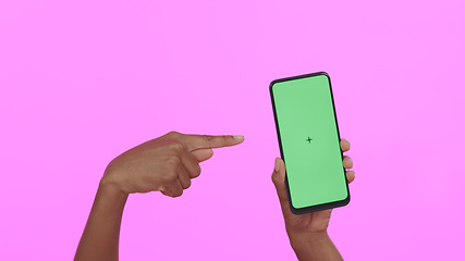 Image showing Hands, pointing at green screen and smartphone, advertising mockup with app and ads on pink background. Tracking marker, person in studio with online information for website and tech marketing