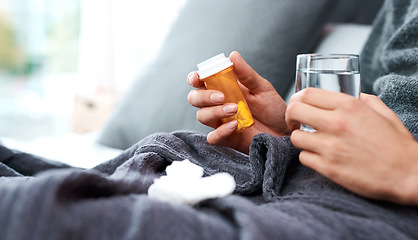 Image showing Keep your fluid intake up and your exertion levels low. an unrecognisable man taking medication while recovering from an illness in bed at home.