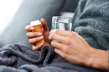 Image showing Take down the virus Challenge accepted. an unrecognisable man taking medication while recovering from an illness in bed at home.