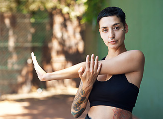 Image showing You cant ball without warming up. Cropped portrait of an attractive young female athlete stretching while standing on the basketball court.