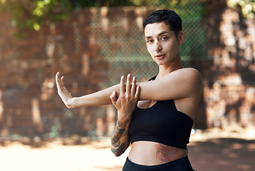 Image showing Going through her warmup routine. Cropped portrait of an attractive young female athlete stretching while standing on the basketball court.