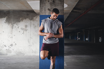 Image showing Time to get in shape. a handsome young sportsman checking his watch while exercising inside a parking lot.