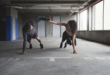 Image showing Teamwork makes the dream work. Full length shot of a sporty young couple exercising together inside an underground parking lot.