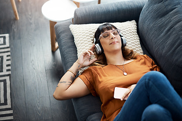 Image showing Nothing is as relaxing as listening to soul music. a young woman wearing headphones while relaxing at home.