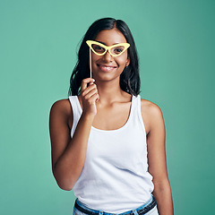 Image showing Now Im stylin. Studio portrait of a beautiful young woman posing with prop glasses against a green background.