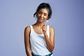 Image showing Sweet things just make me sweeter. Studio portrait of a beautiful young woman sucking on a lollipop against a purple background.