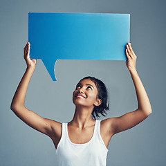 Image showing Say what youve gotta say. Studio shot of a beautiful young woman holding up a blank signboard against a grey background.