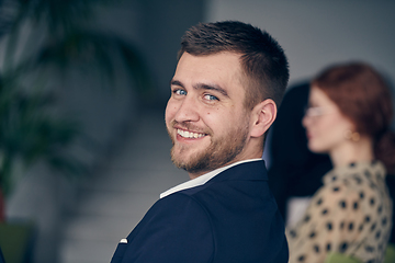 Image showing A smiling entrepreneur sits in a modern office, actively participating in a business meeting, radiating confidence and professionalism.