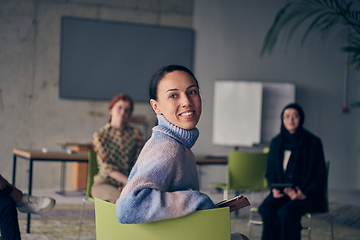 Image showing A young female entrepreneur is attentively listening to a presentation by her colleagues, reflecting the spirit of creativity, collaboration, problem-solving, entrepreneurship, and empowerment.
